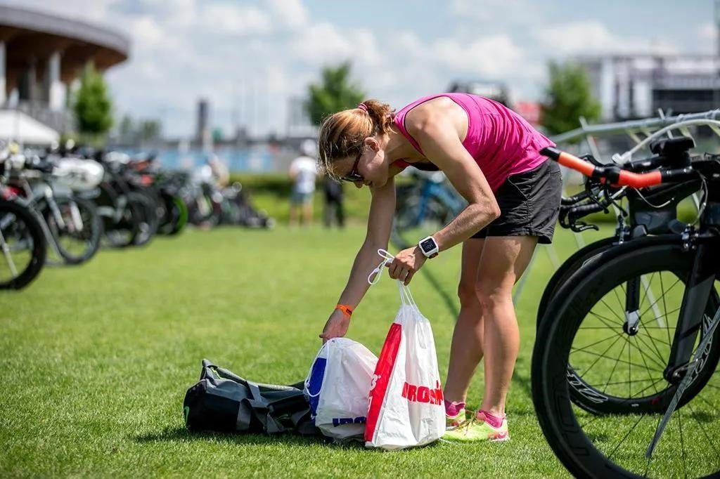 Triathlete preparing a transition bag and race-day gear in the transition area before the start of a triathlon.