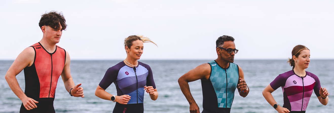 Triathletes competing in a race while wearing sleeved and sleeveless triathlon suits, highlighting different race-day apparel choices.
