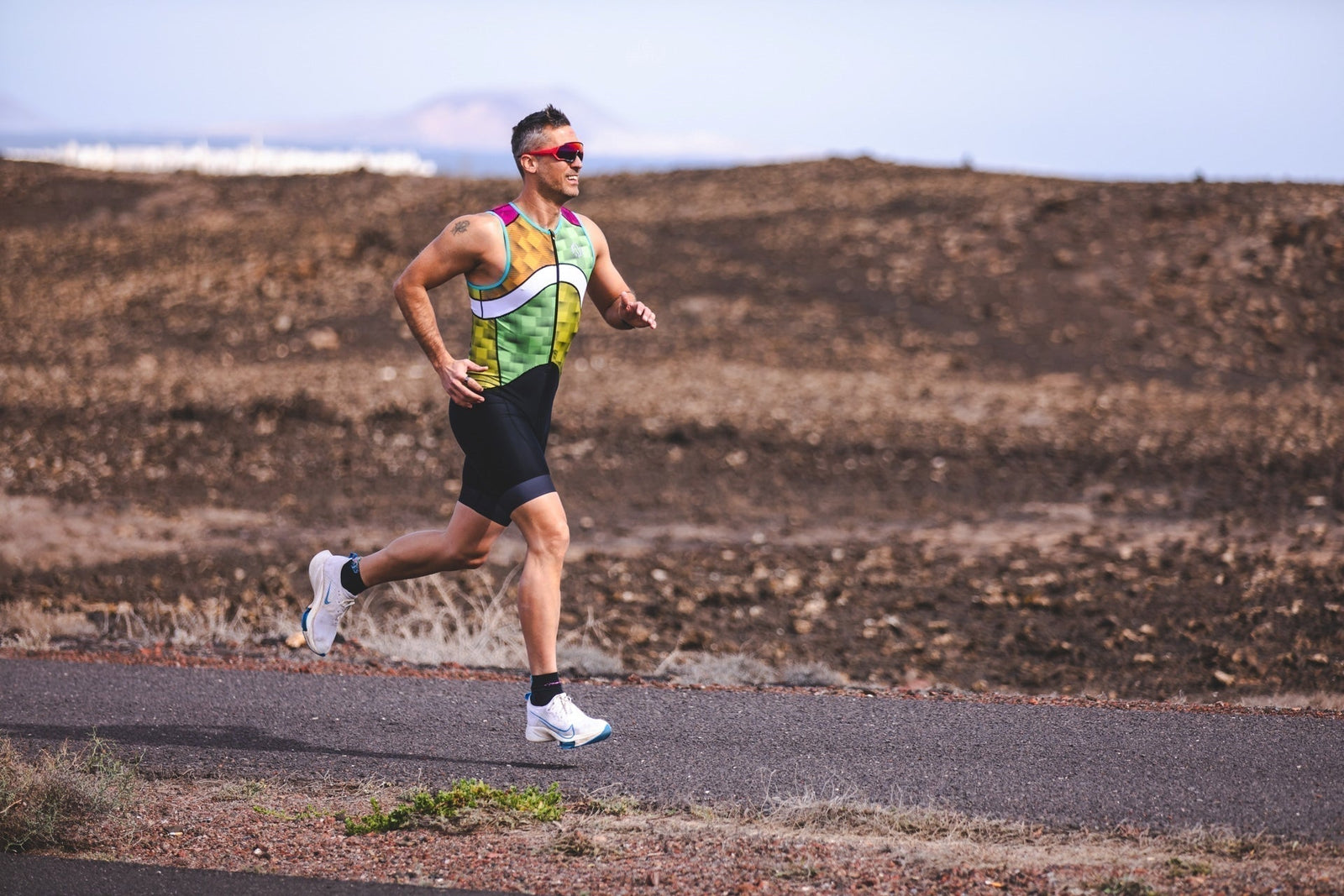  Athlete running in a tri suit during training, demonstrating efficient running form and endurance performance.