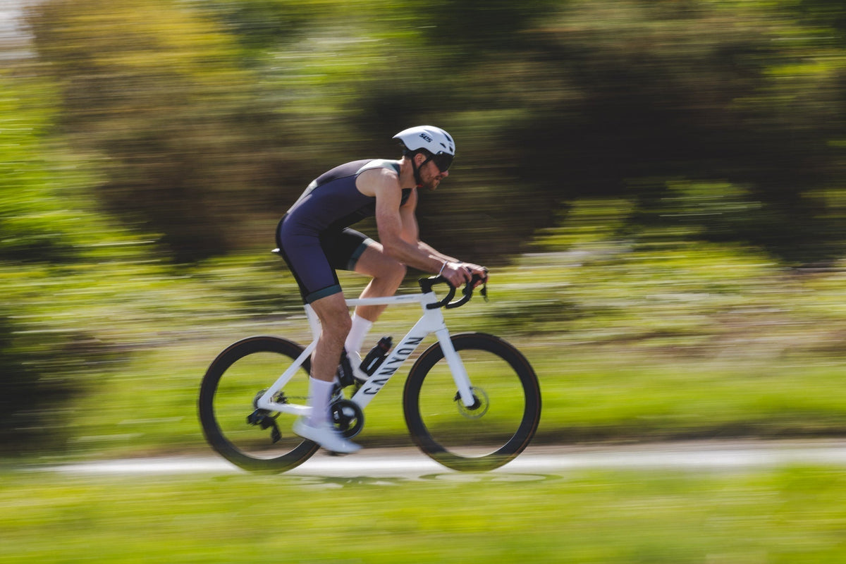 Triathlete riding a road bike in an aerodynamic position during a high-speed training session, demonstrating the disciplined endurance training associated with the Norwegian method.